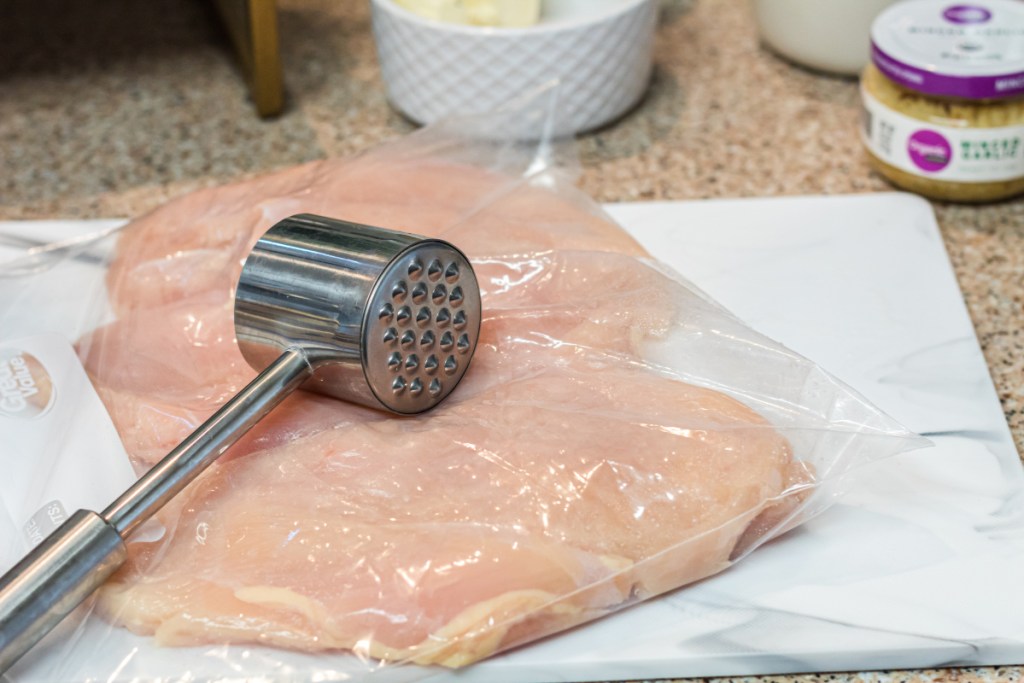 meat mallet on top of sealed chicken in a zip locked bag