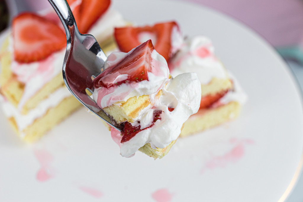 strawberry shortcake chaffle on fork withe whipped cream and fresh strawberries