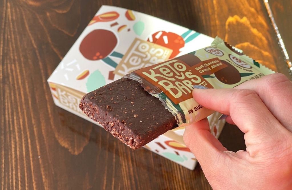 A hand holding a chocolate keto snack bar