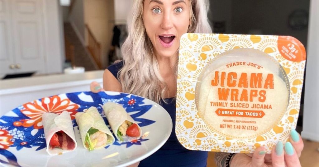 A woman holding jicama wraps and a plate of tacos