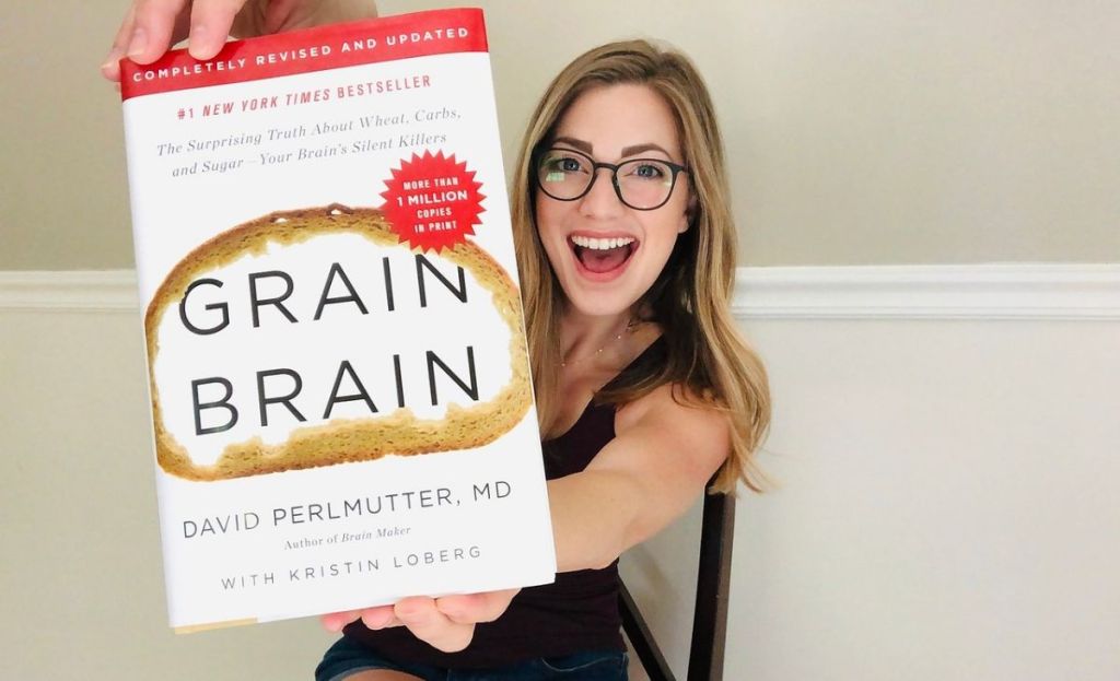 A woman holding a hard copy of Grain Brain