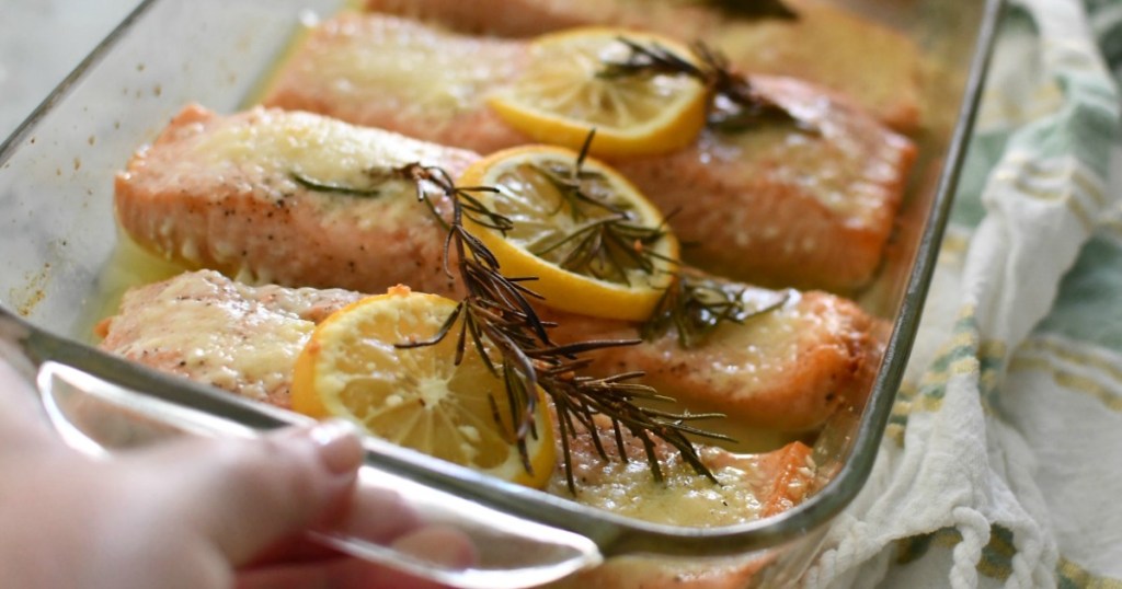 pulling out baked salmon with lemons
