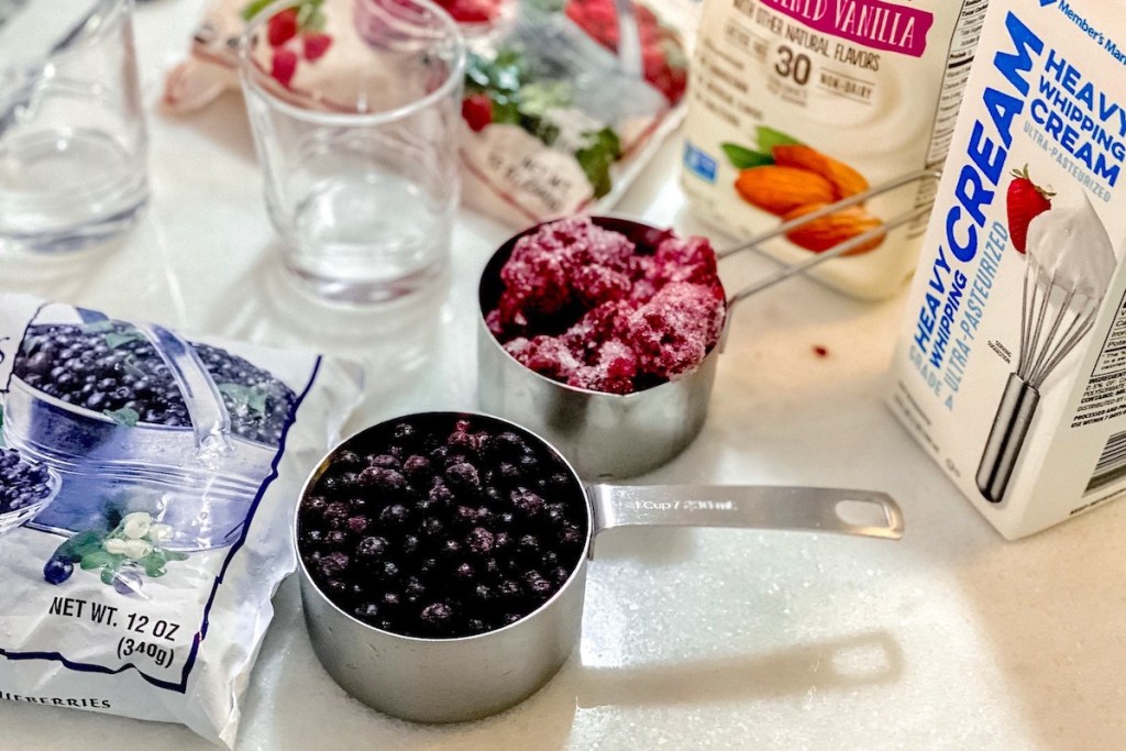 two stainless steel measuring cups with berries inside