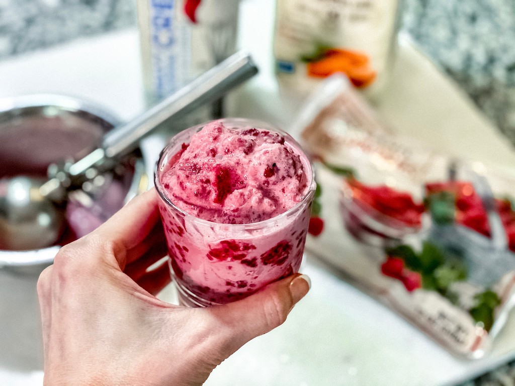 holding cup of raspberry keto ice cream