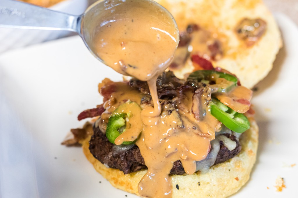 drizzling peanut butter sauce over hamburger