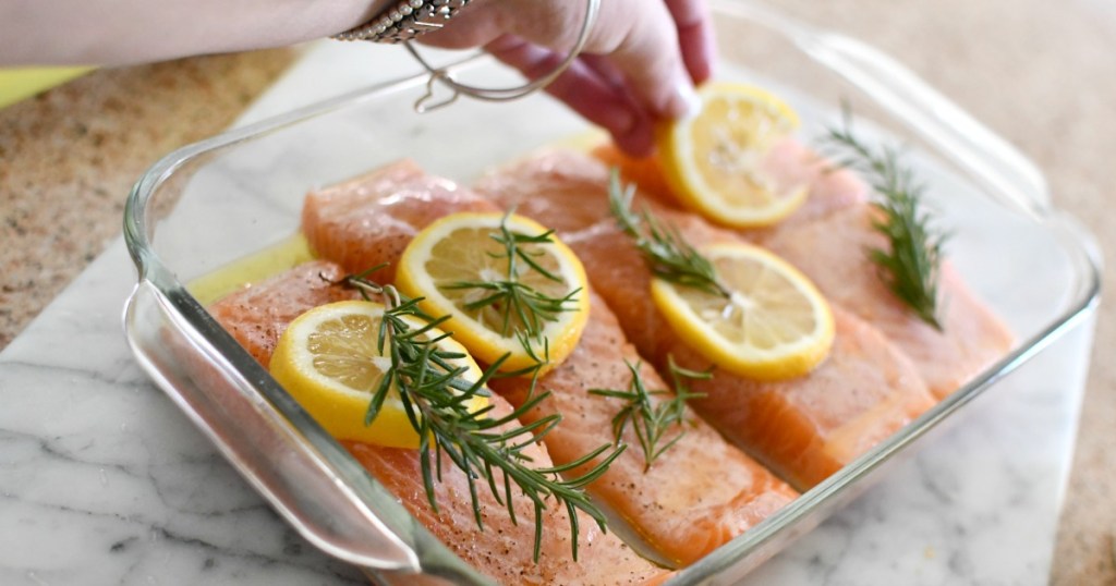 placing lemon slices and sprigs of rosemary on top of the salmon