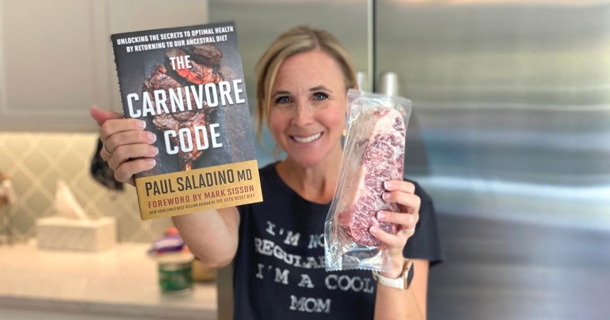 A woman holding a book in one hand and a raw steak in the other hand