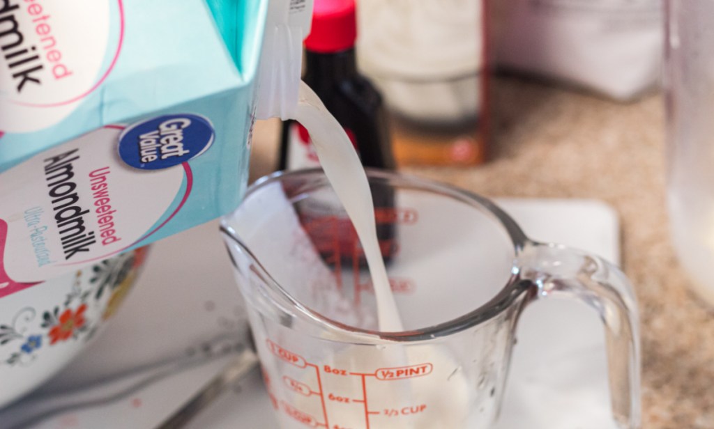Pouring almond milk into a measuring cup