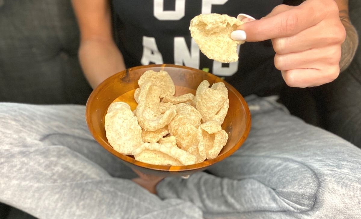 A person sitting with a bowl of pork rinds