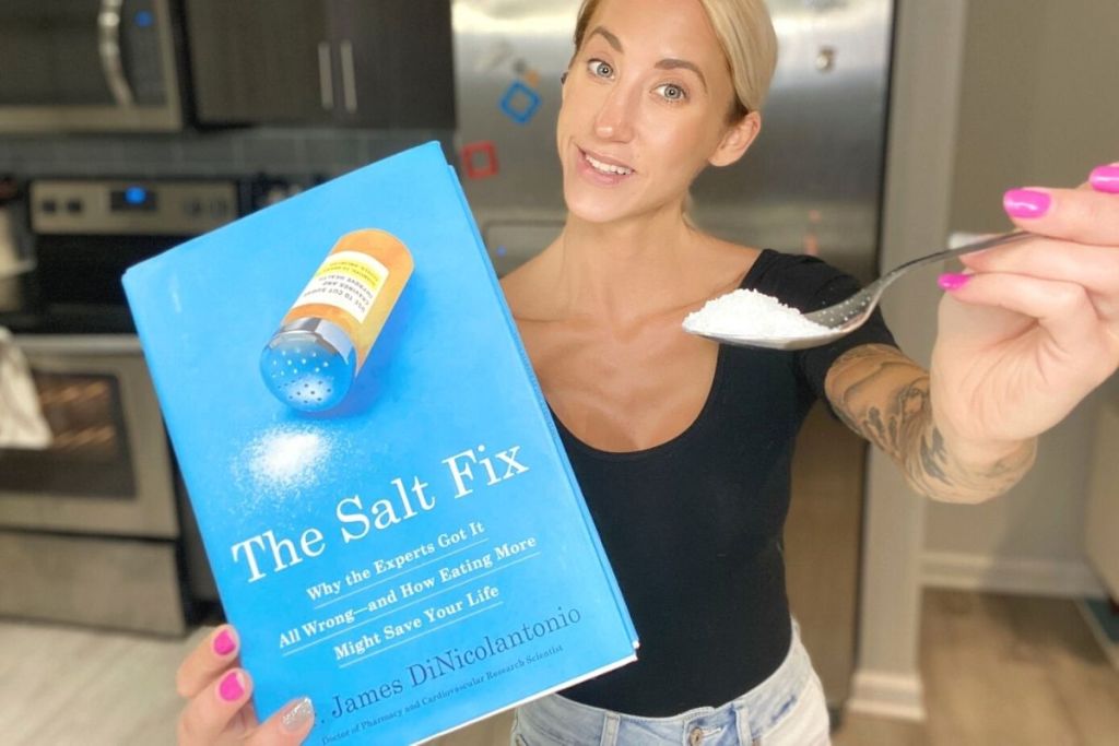 A woman holding a book and a spoonful of salt