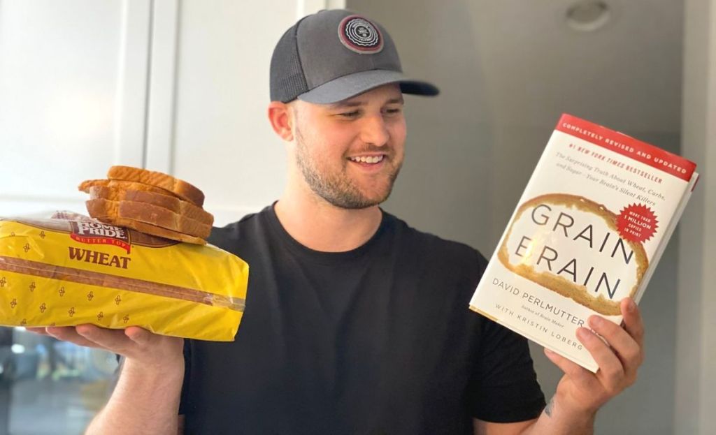 A man holding a book in one hand and bread in the other hand