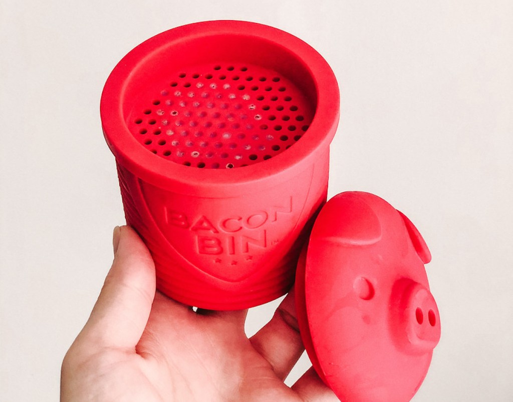 hand holding red pig shaped bacon bin with strainer on top