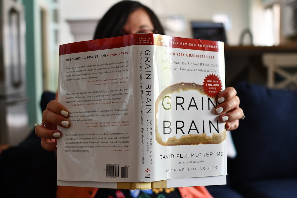 woman holding Grain Brain hardcover book 