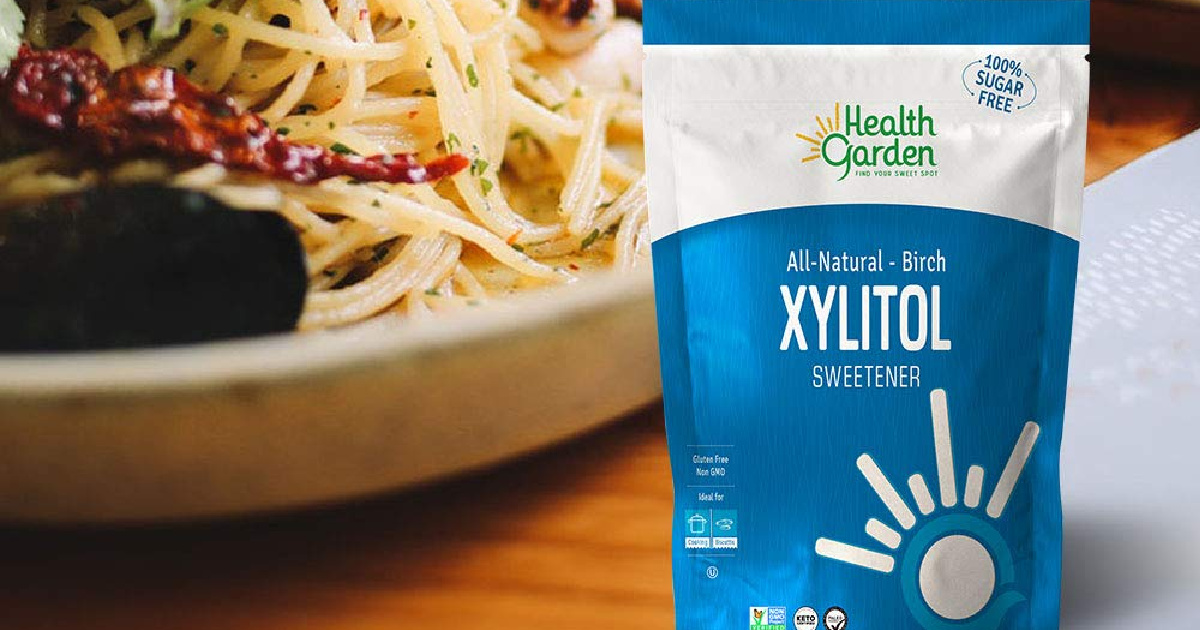 Health Garden Xylitol Sweetener Bag on wood counter with bowl of pasta in background