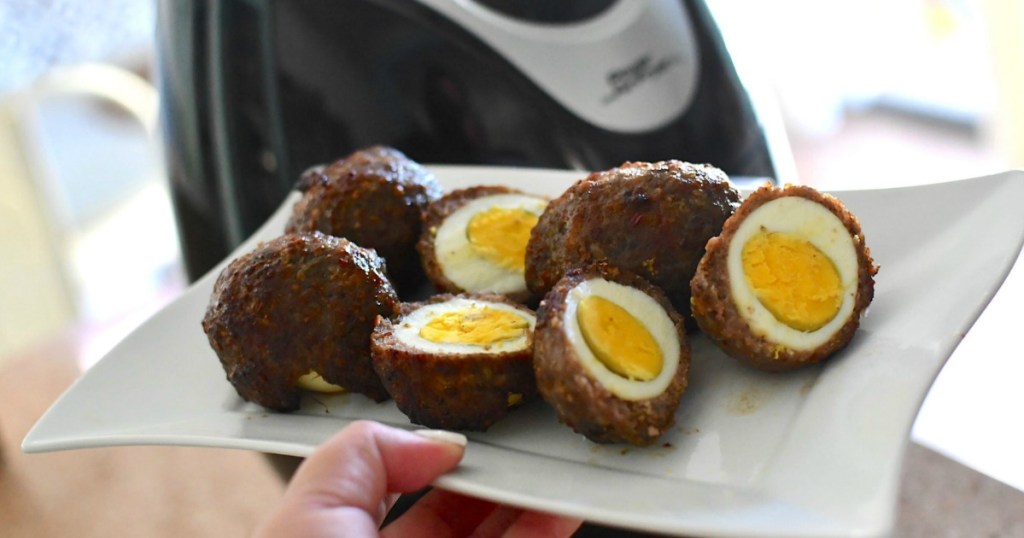 holding plate of scotch eggs in front of air fryer