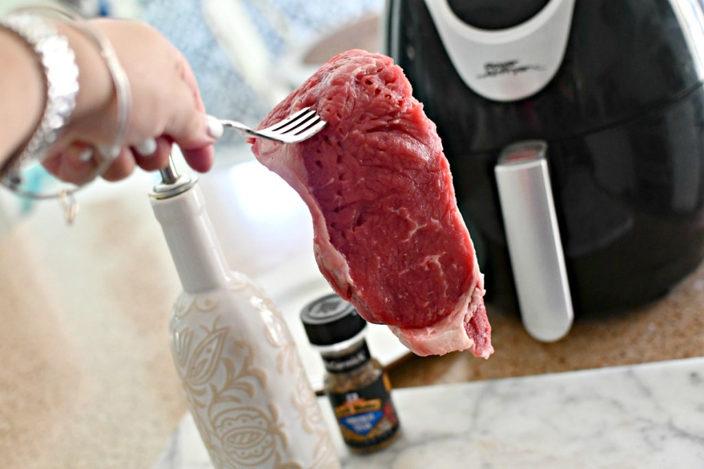 holding up a steak to air fryer