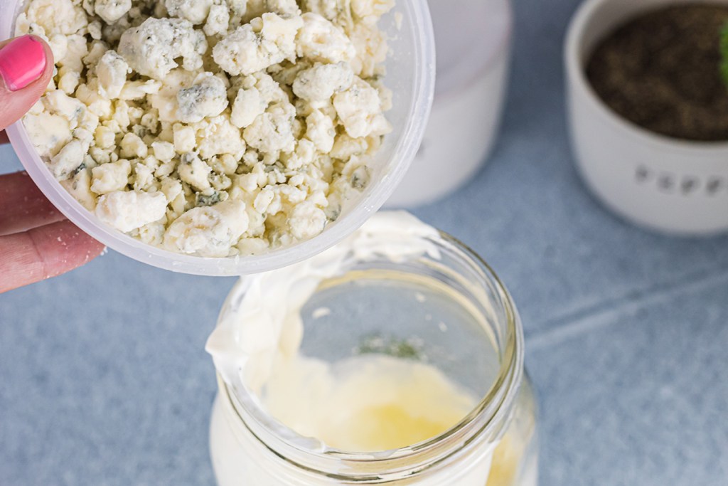 pouring in bleu cheese crumbles into dressing