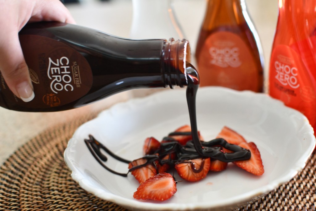pouring ChocZero sugar free chocolate syrup on strawberries