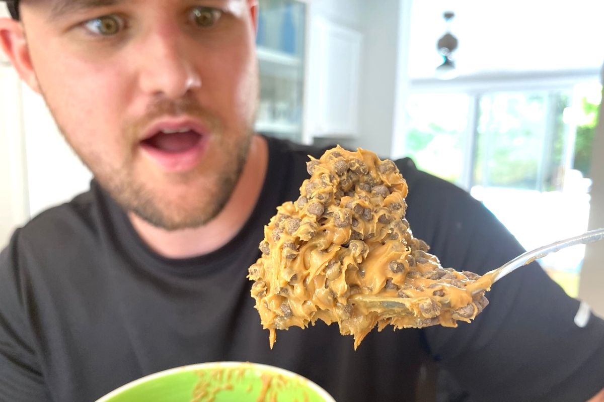 A man holding a spoonful of peanut butter with protein puffs in it