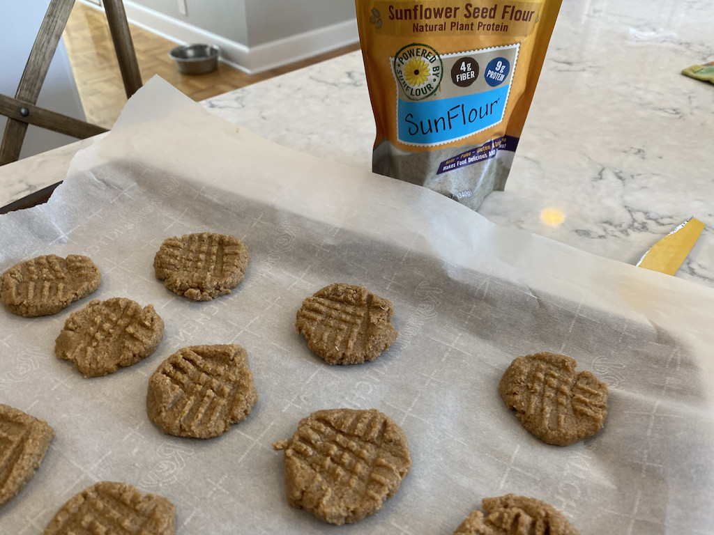 sunflower seed flour on counter with peanut butter cookies on pan