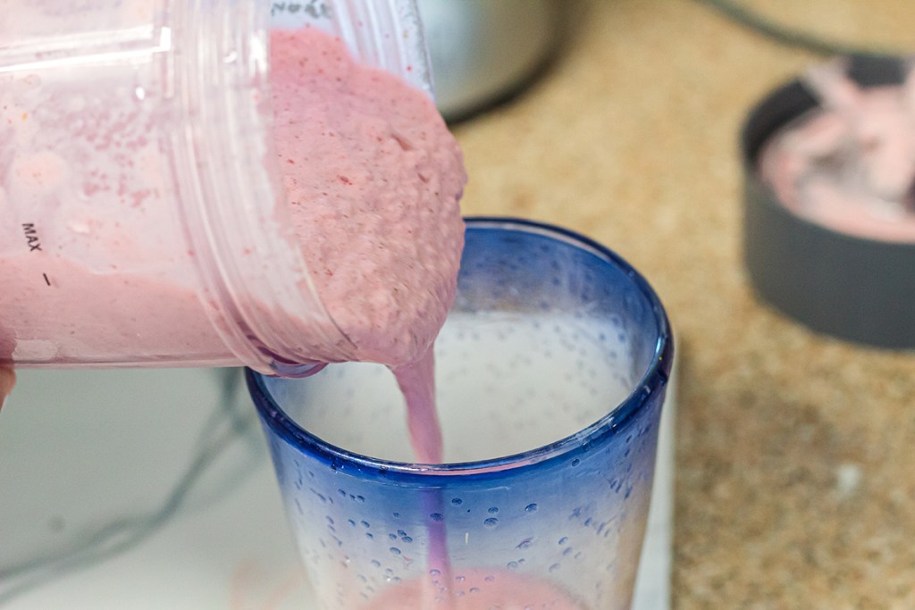 pouring strawberry banana smoothie into glass