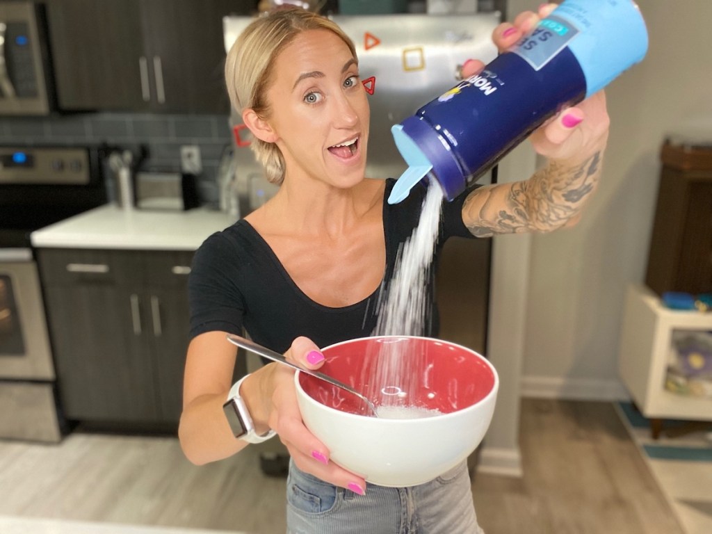 woman pouring corse sea salt into red and white bowl