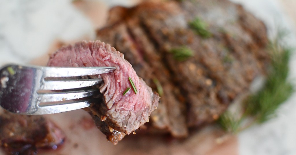 fork holding up piece of steak from the air fryer