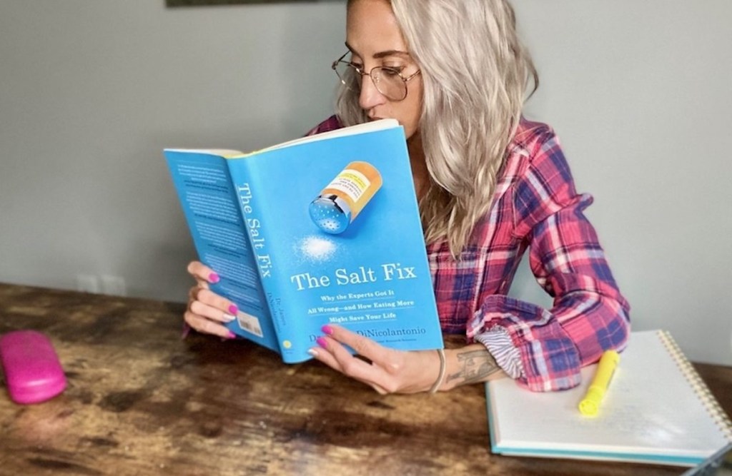 woman holding blue the salt fix book wearing glasses and plaid shirt