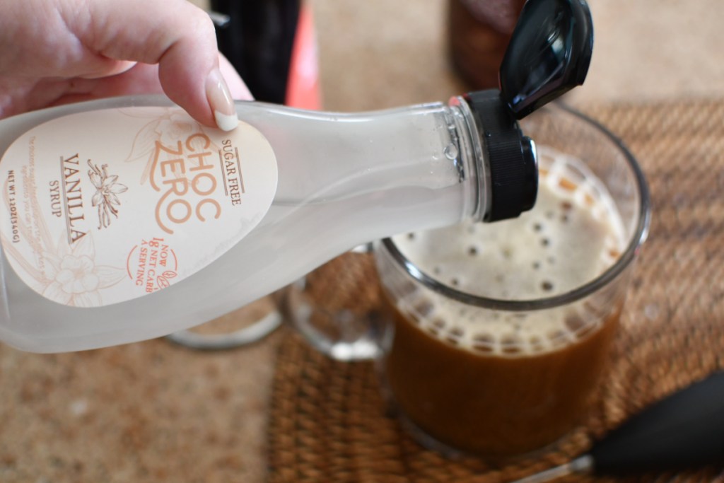 pouring sugar-free vanilla syrup into coffee