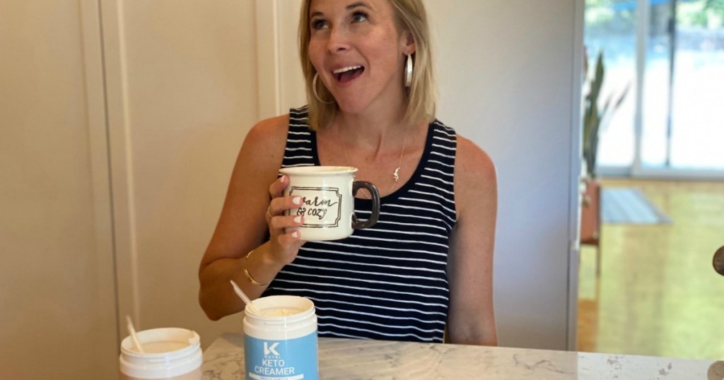 woman holding coffee cup with keto coffee creamer on counter 