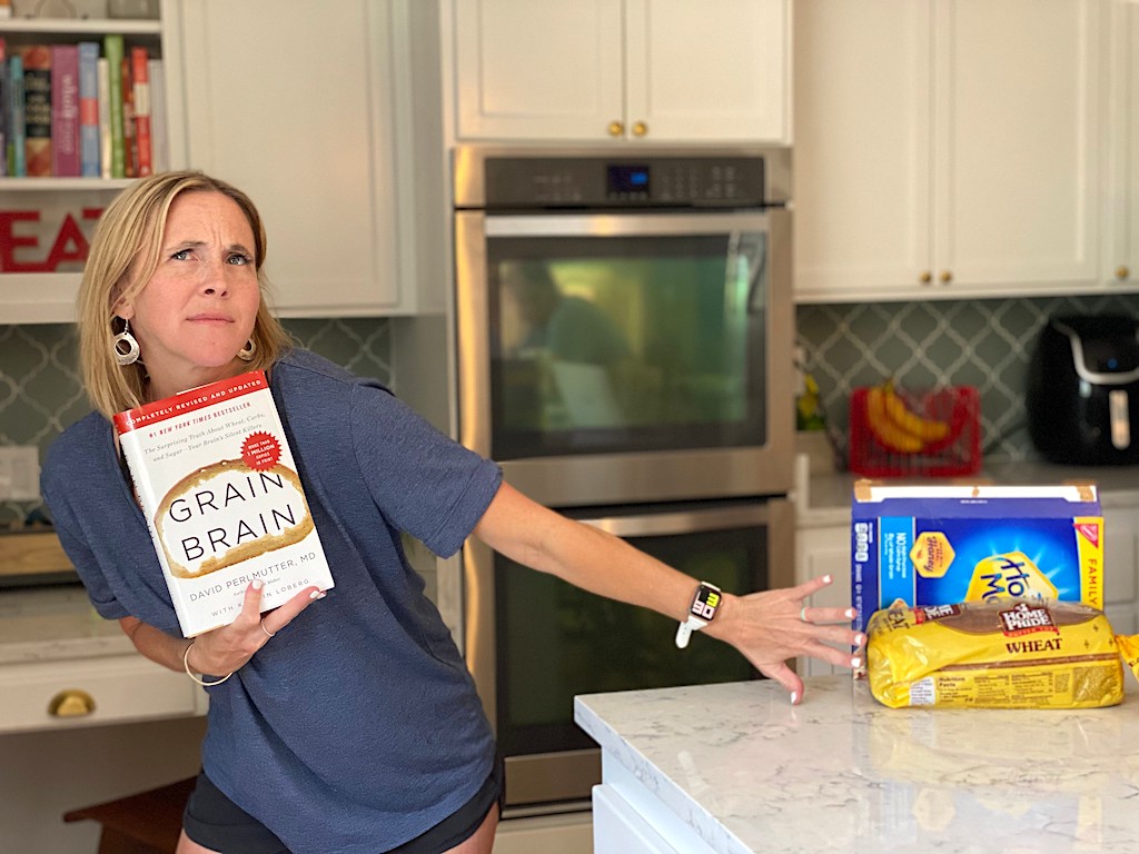 woman holding Brain Grain book while pushing away carbs