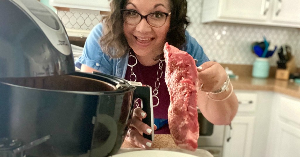 woman putting a steak in the air fryer