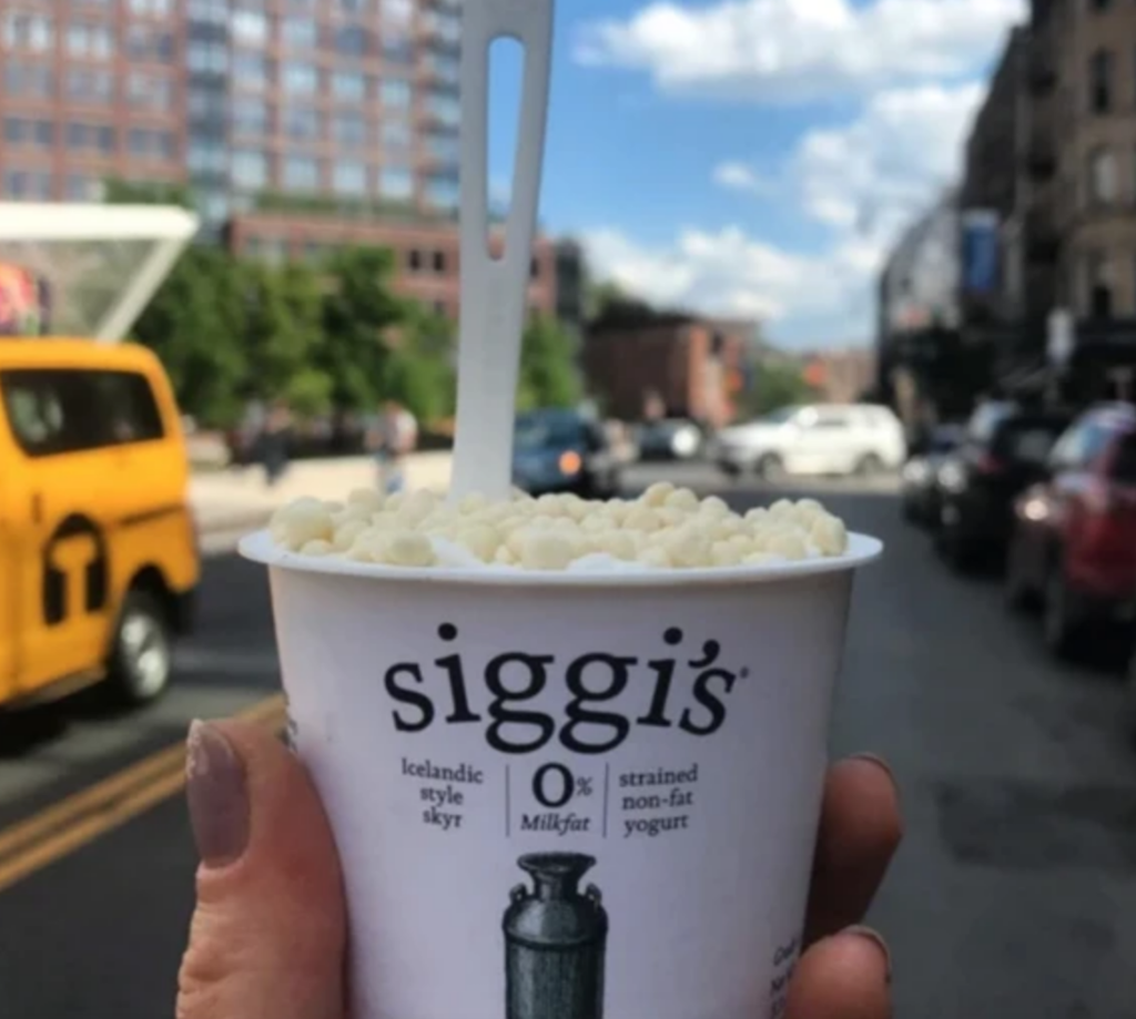 holding Siggi's yogurt with protein puffs inside 