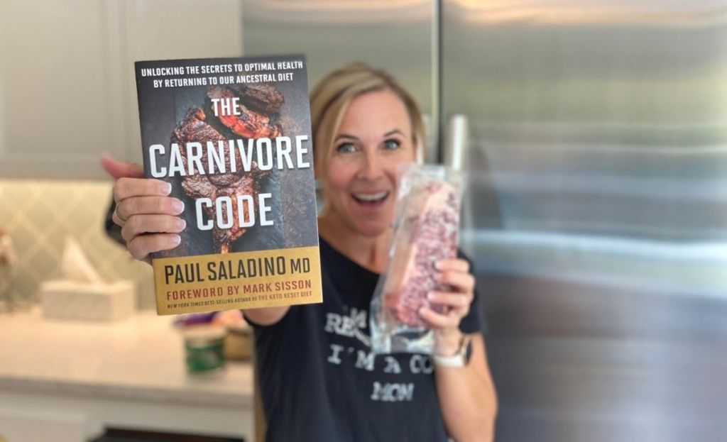 A woman holding a book in one hand and steak in the other hand