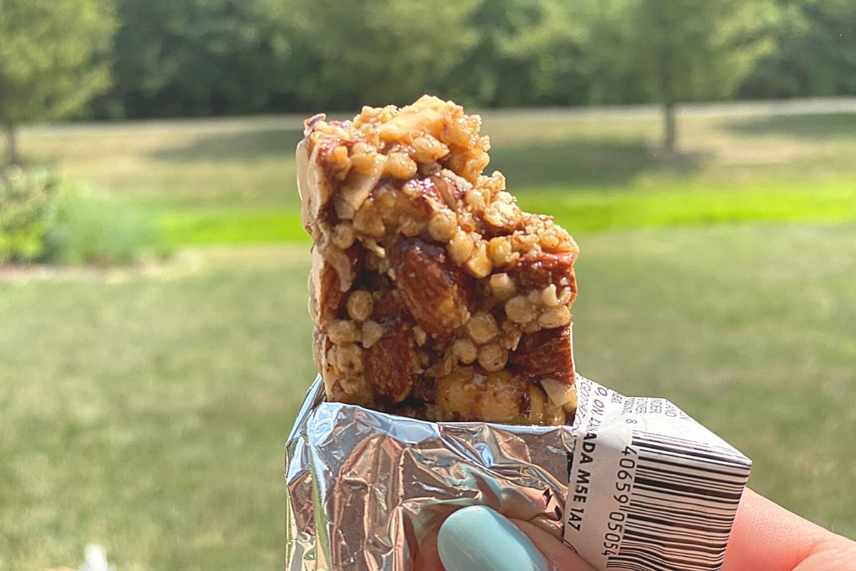 A hand holding an open nut bar in the wrapper