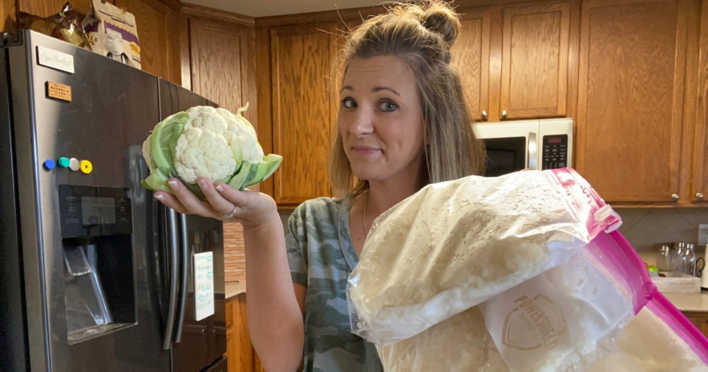 woman holding a cauliflower and bag of cauliflower rice