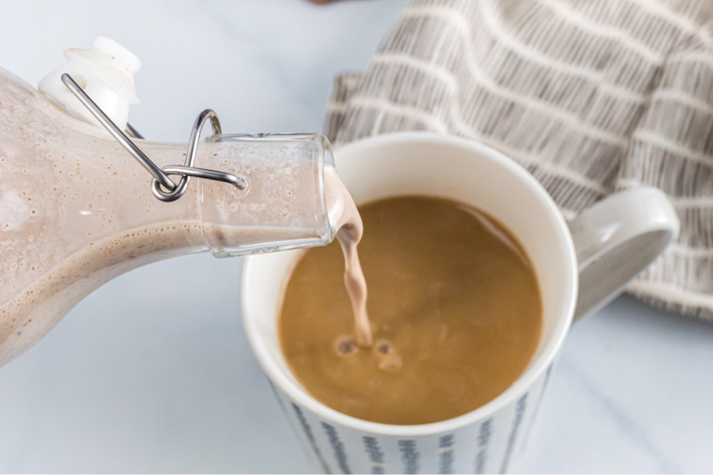 creamer being poured into a cup of coffee