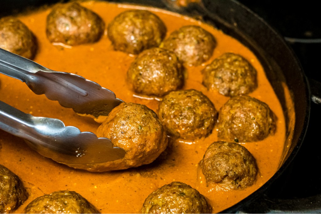 adding meatballs to pumpkin sauce