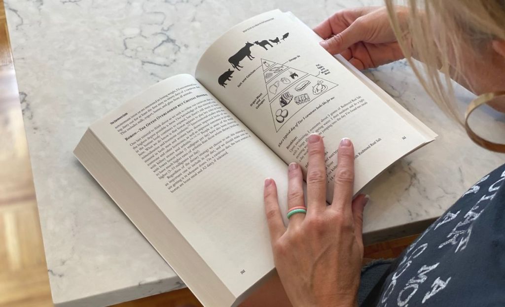 A woman reading a page from a book at a table