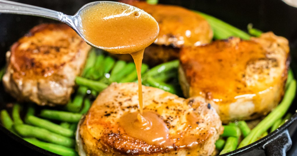 spooning peach sauce over pork chops in pan