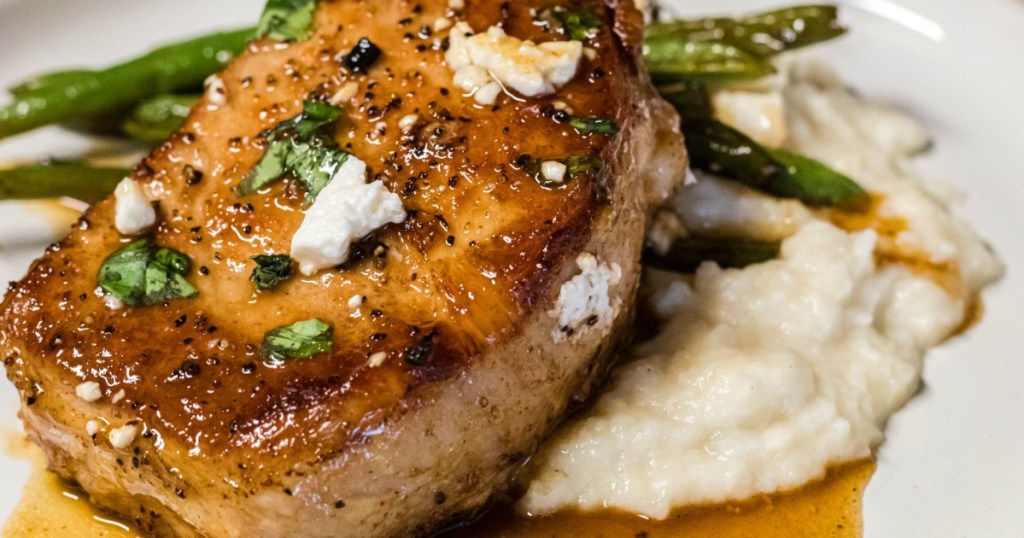 close up of keto peach pork chop on plate with green beans 
