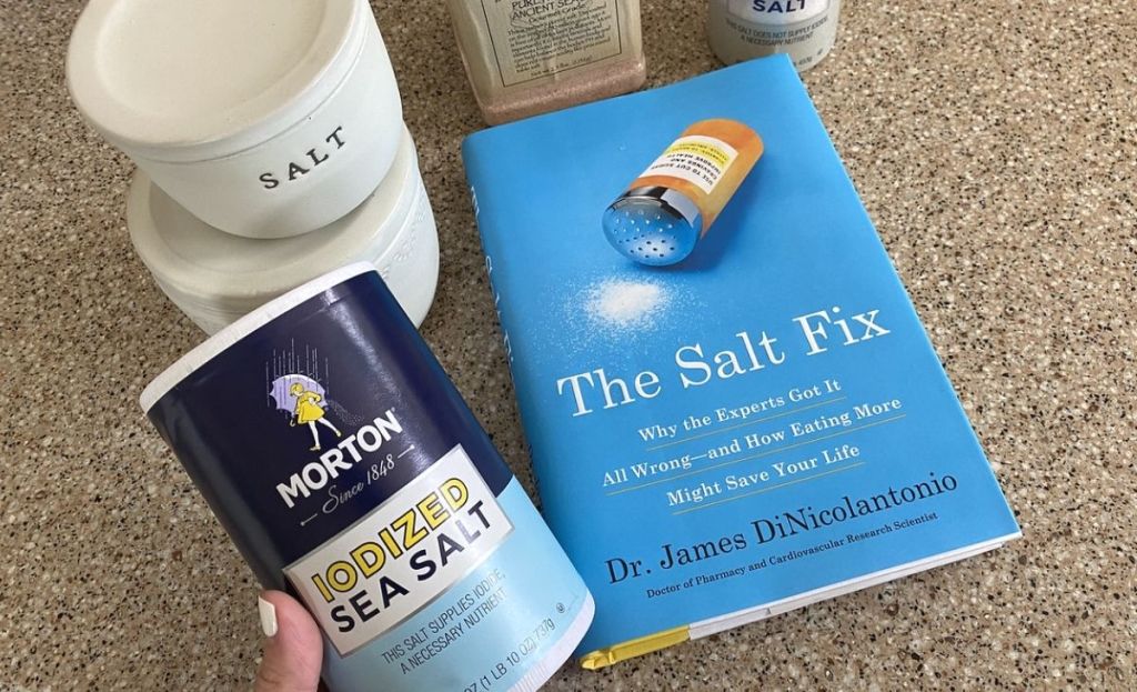 Containers of salt next to a book on the counter