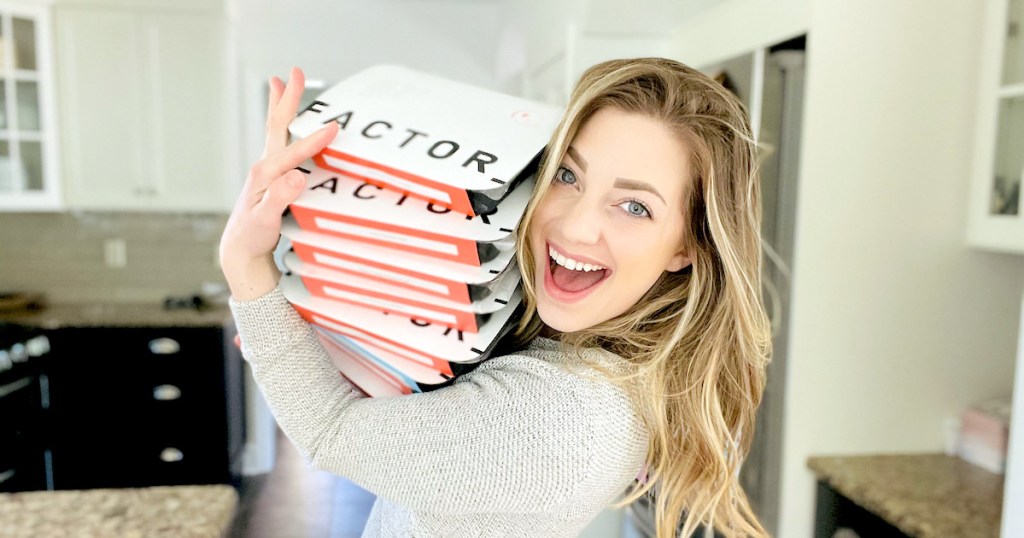 woman smiling holding a stack of factor meals