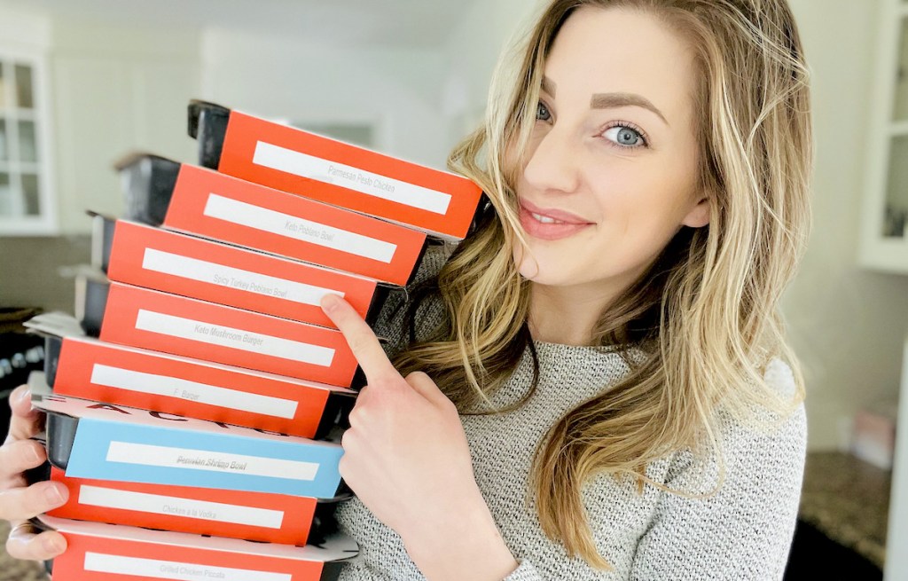 woman holding and pointing to stack of frozen factor meals