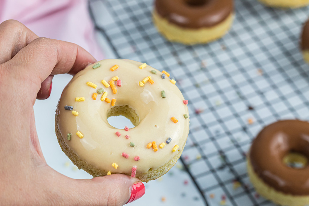 holding keto donut with frosting and sprinkles
