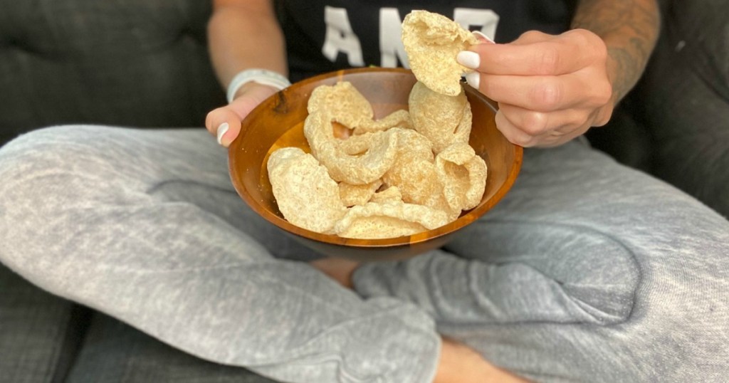 person holding bowl of pork rinds