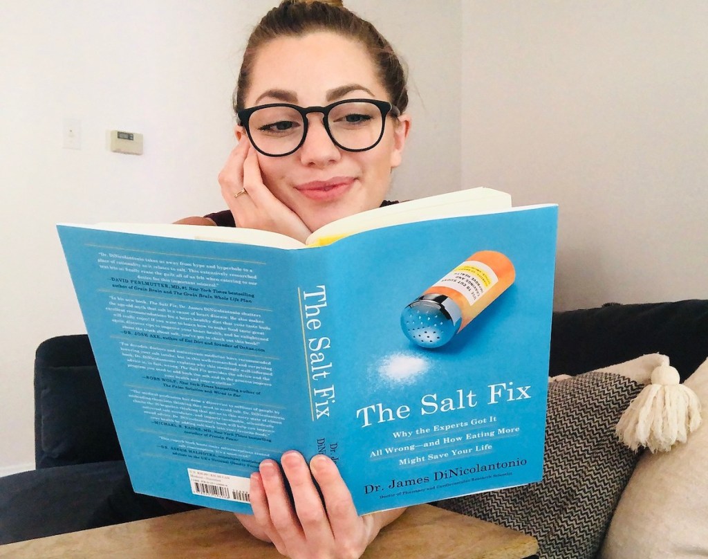woman with hand on chin reading the salt fix book