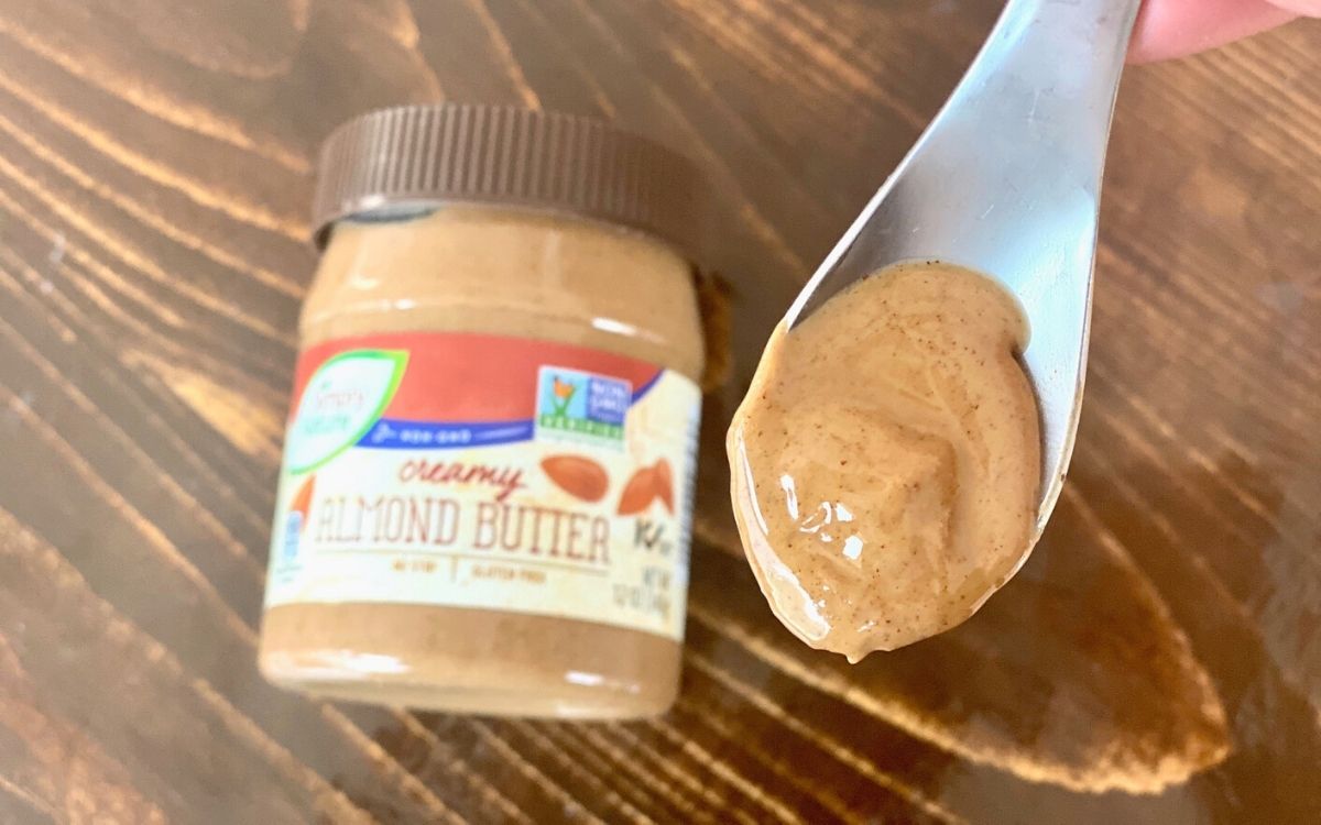 A spoonful of nut butter next to the jar on a table
