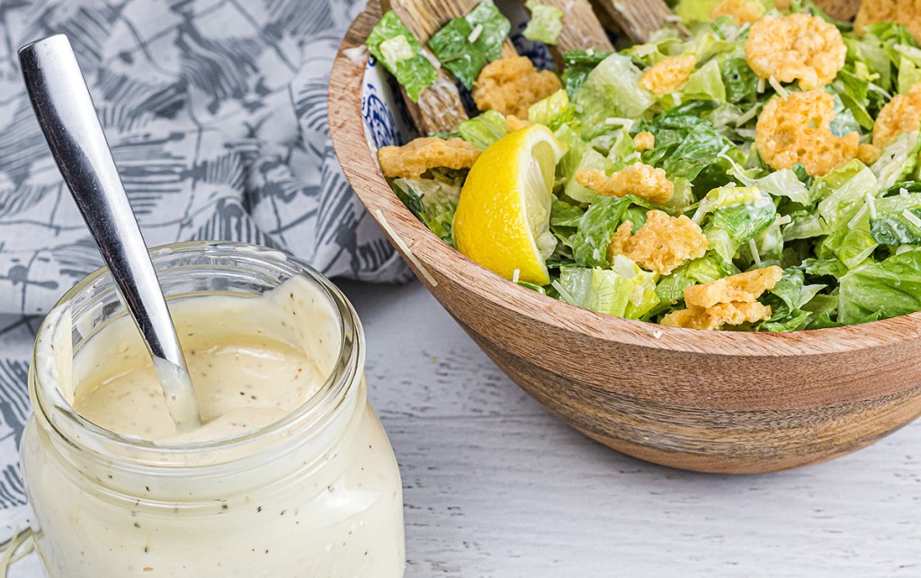 jar of keto dressing next to bowl of salad