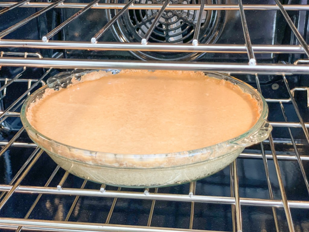 pouring easy keto pumpkin pie filling into pie crust